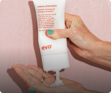 Een hand knijpt shampoo uit een witte fles met het merk "evo" op een andere hand.
