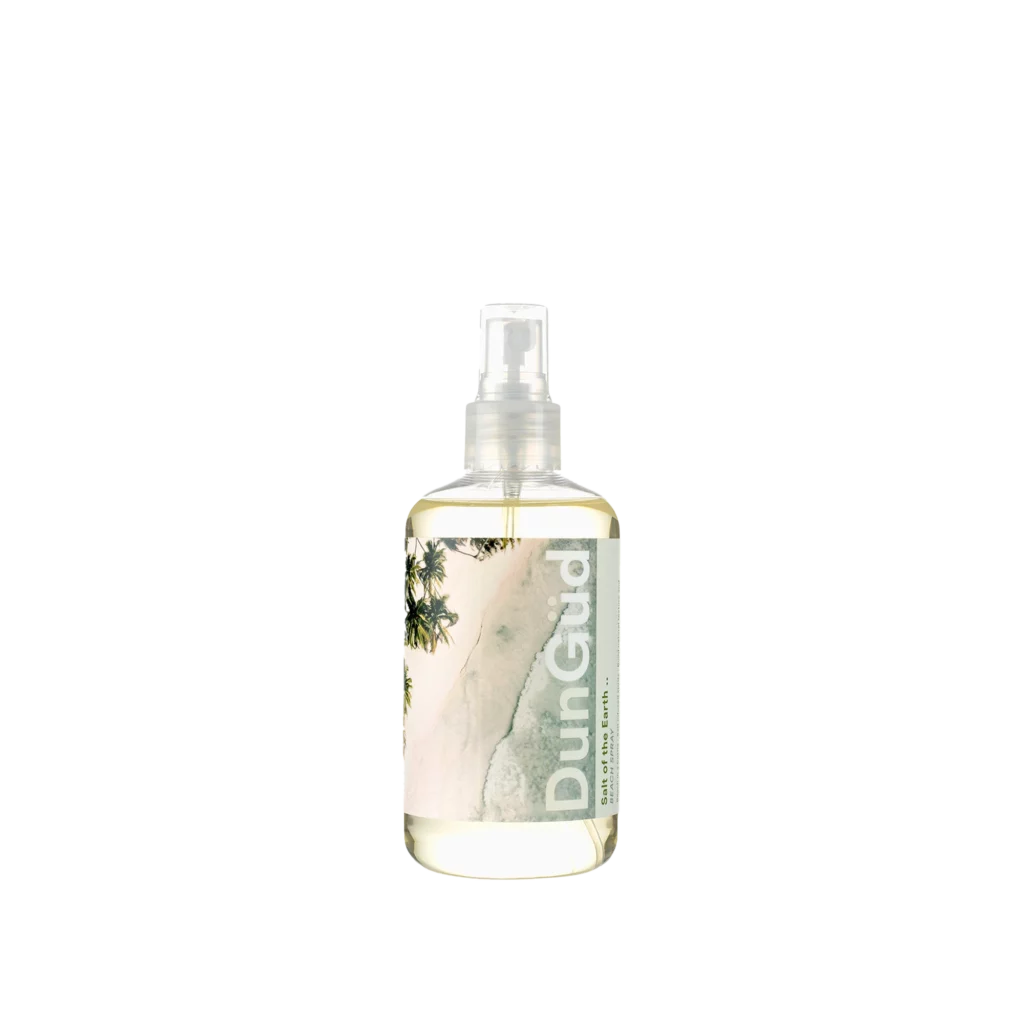 Transparante sprayfles van DunGüd met het label "Salt of the Earth Texture Spray" en een strandachtige afbeelding op de achtergrond.