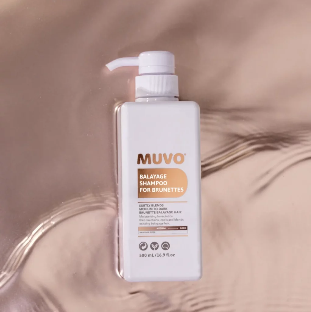 Witte fles MUVO Balayage Shampoo for Brunettes van 500 ml op een glanzende, lichtroze achtergrond.
