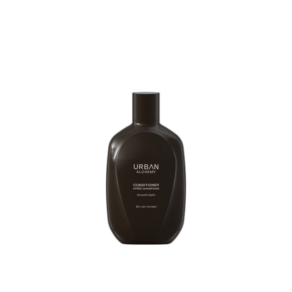 Zwarte fles Urban Alchemy Smooth Satin conditioner met minimalistisch etiket op een zwarte achtergrond.